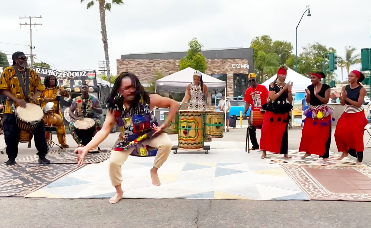 Juneteenth celebration in downtown Encinitas with West African dancers, drummers, and community members gathered outdoors.